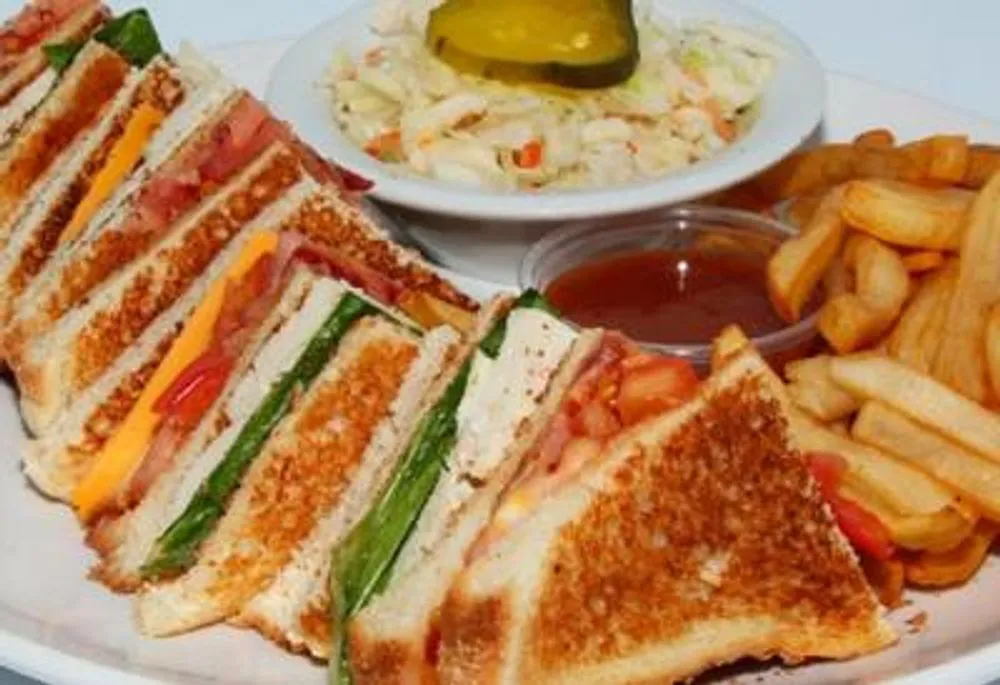 Triple-decker club sandwich platter with fries, coleslaw and pickle spear at Pizzeria 67, a Pizza Restaurant in Grand-Mère