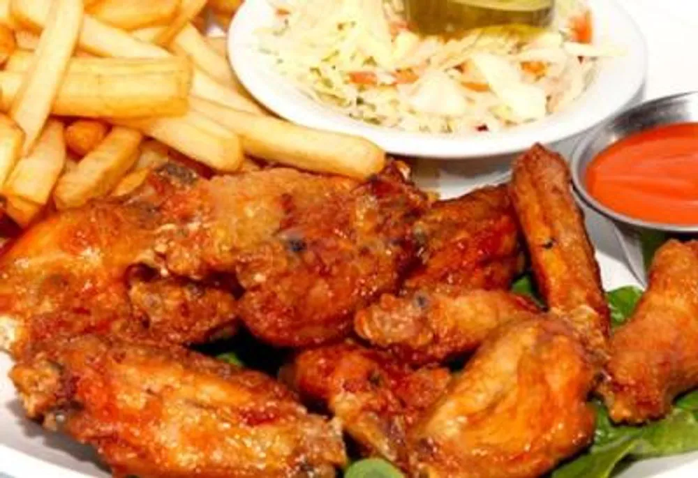 Spicy fried chicken wings served with fries, coleslaw and hot sauce at Pizzeria 67, a Pizza Restaurant in Grand-Mère